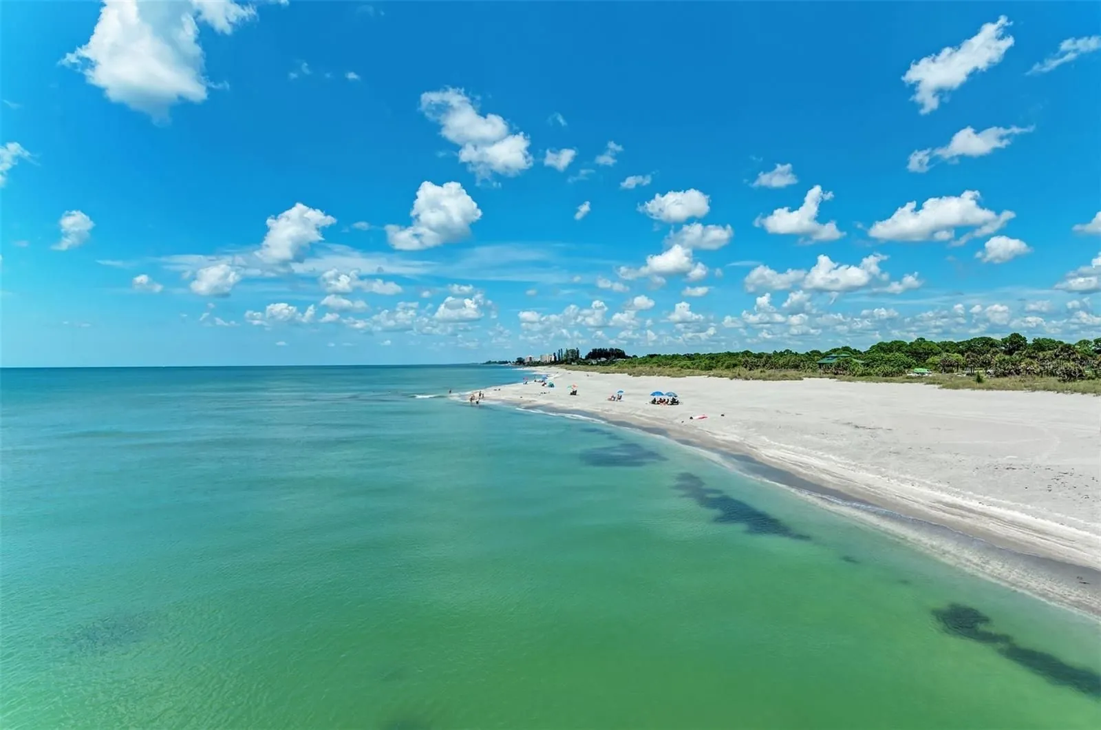 Clear green Gulf water meeting a wide sandy beach on Manasota Key